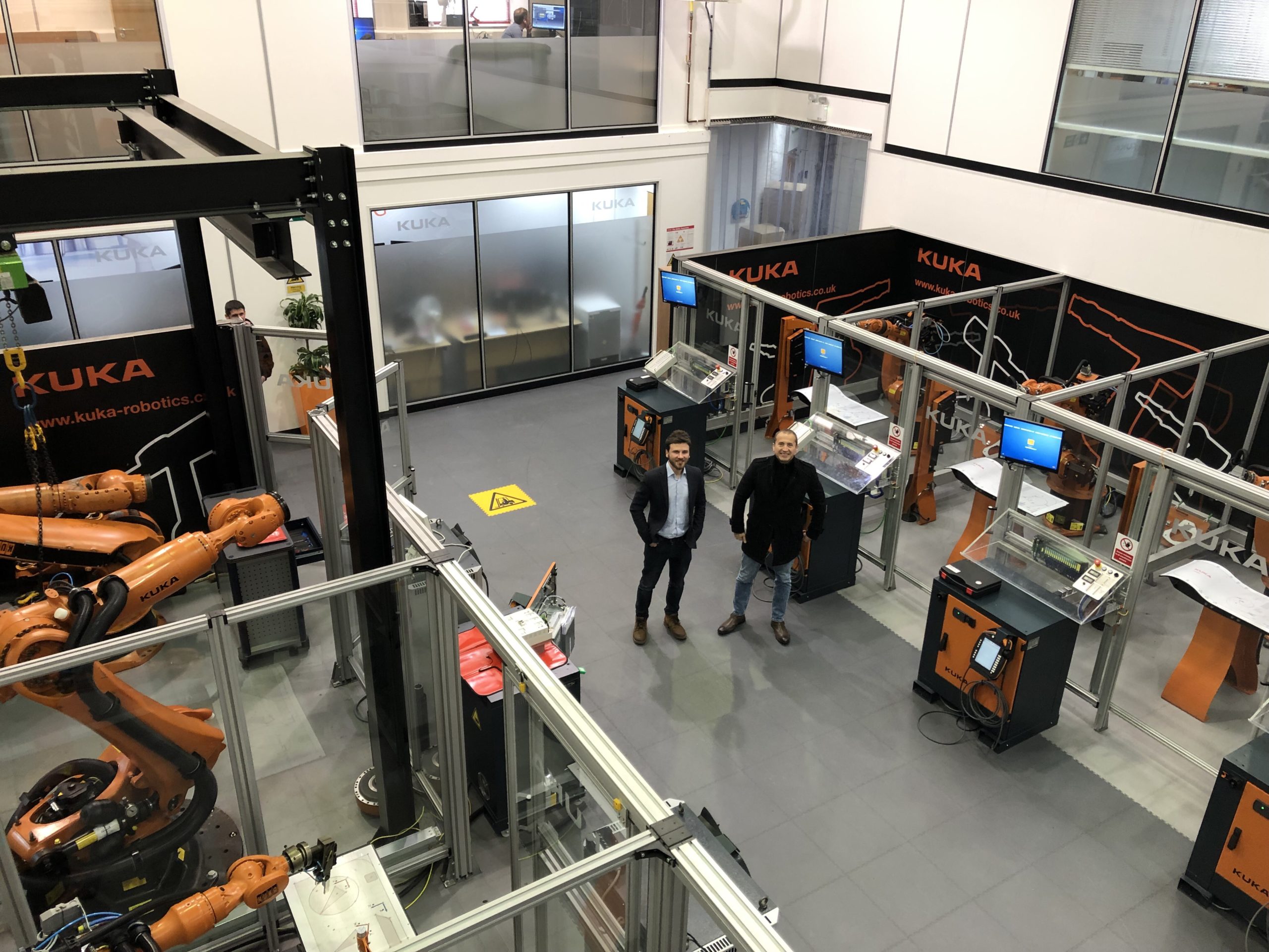 Deux personnes entre des cellules robotisées KUKA