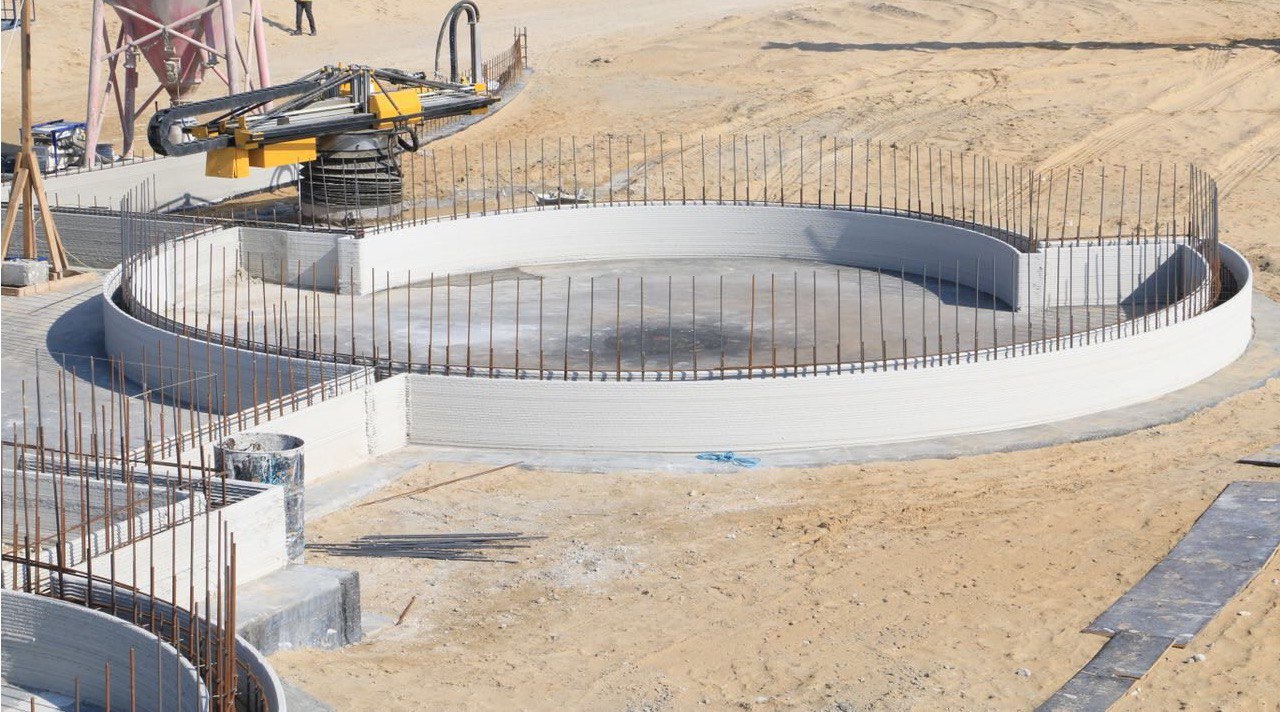 Chantier avec murs courbes imprimés et armatures visibles