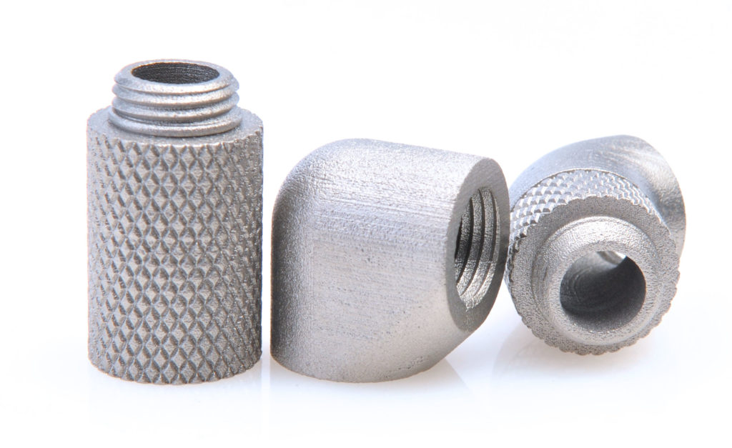 Trois petites pièces métalliques avec surfaces texturées et filetages