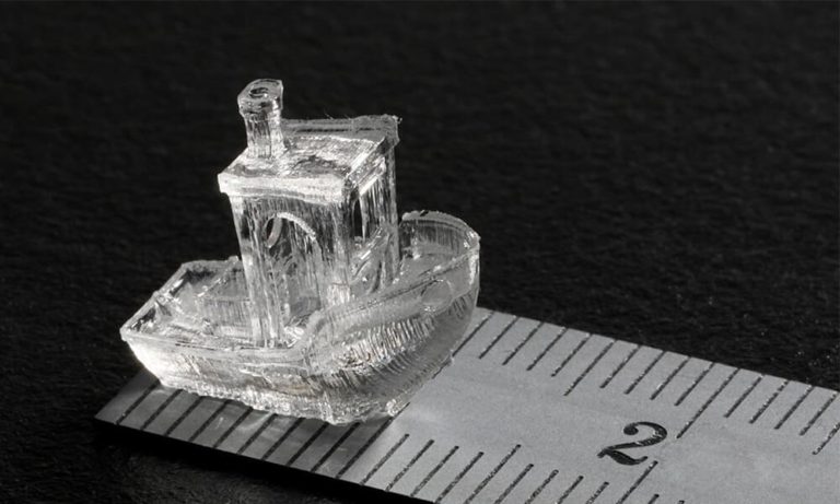 Petit bateau translucide imprimé en 3D, posé près d’une règle graduée