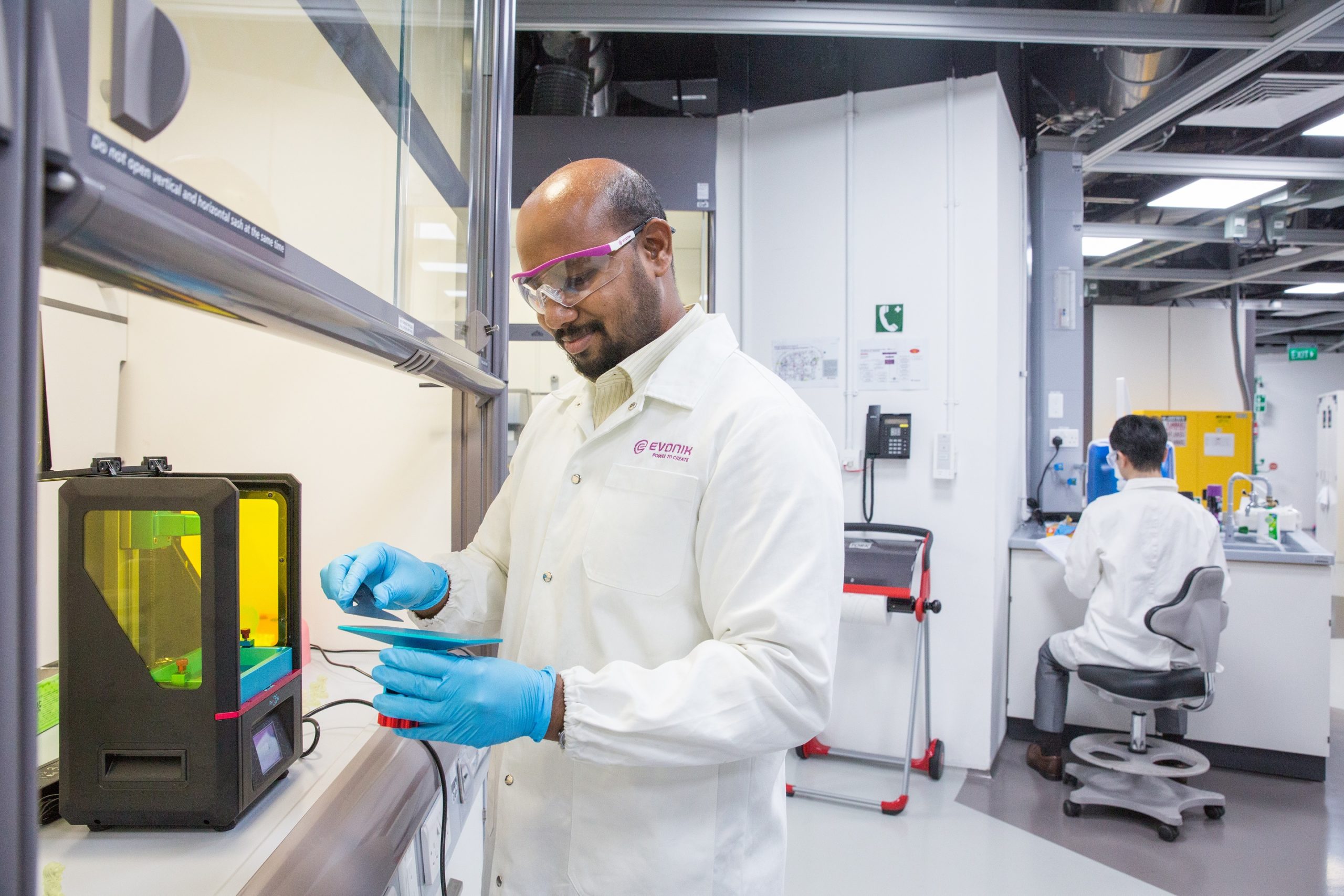 Technician beside an additive manufacturing system in an Evonik laboratory