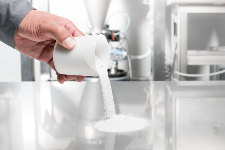 White INFINAM PA12 powder poured into a container at Evonik