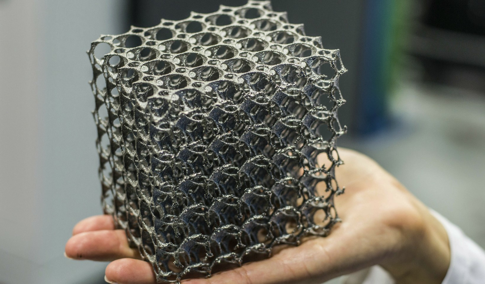 Metal lattice cube held in a hand