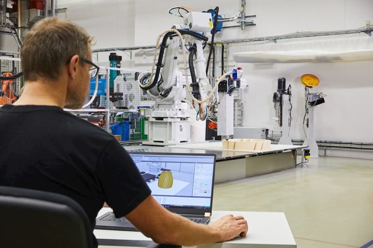 Operator beside an ABB industrial robot and its control interface