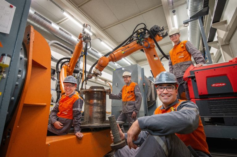 Guaranteed team beside additive manufacturing robots in the workshop