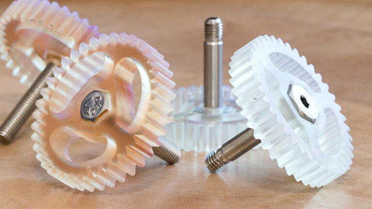Translucent polymer gears displayed beside metal fasteners