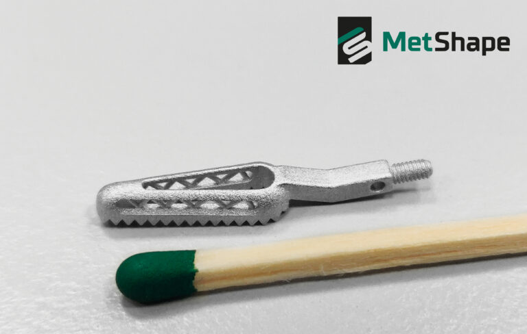 Small MetShape metal component with a threaded end beside a matchstick