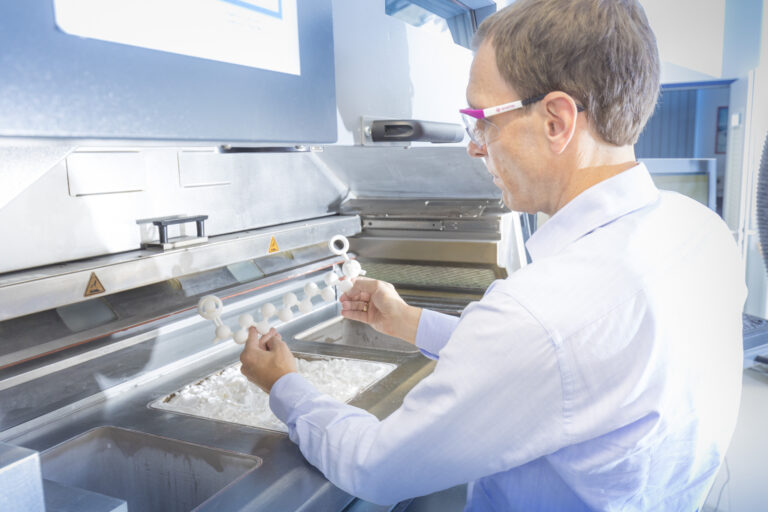 Technician handling polymer powder on additive manufacturing equipment