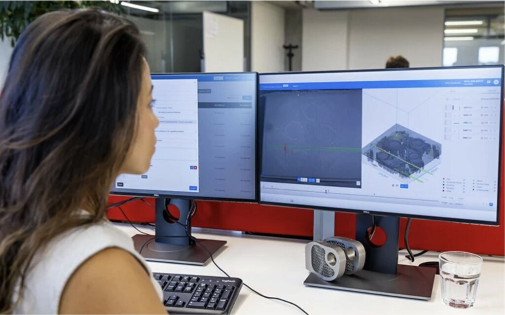 Materialise employee examining manufacturing data on two monitors