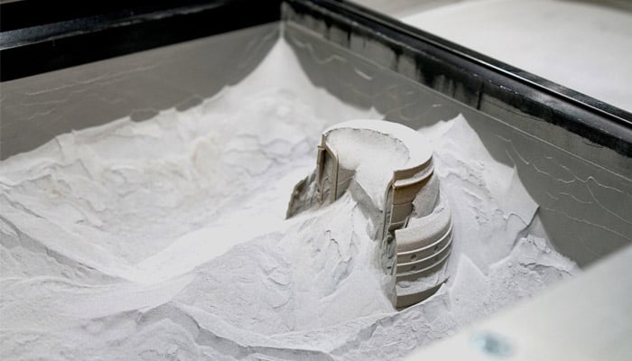 Pièces partiellement dégagées d’un lit de poudre polymère