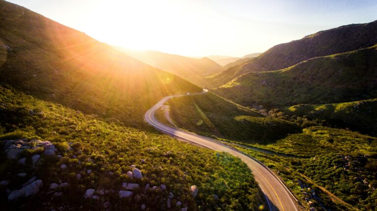 Route sinueuse traversant un paysage de collines au soleil