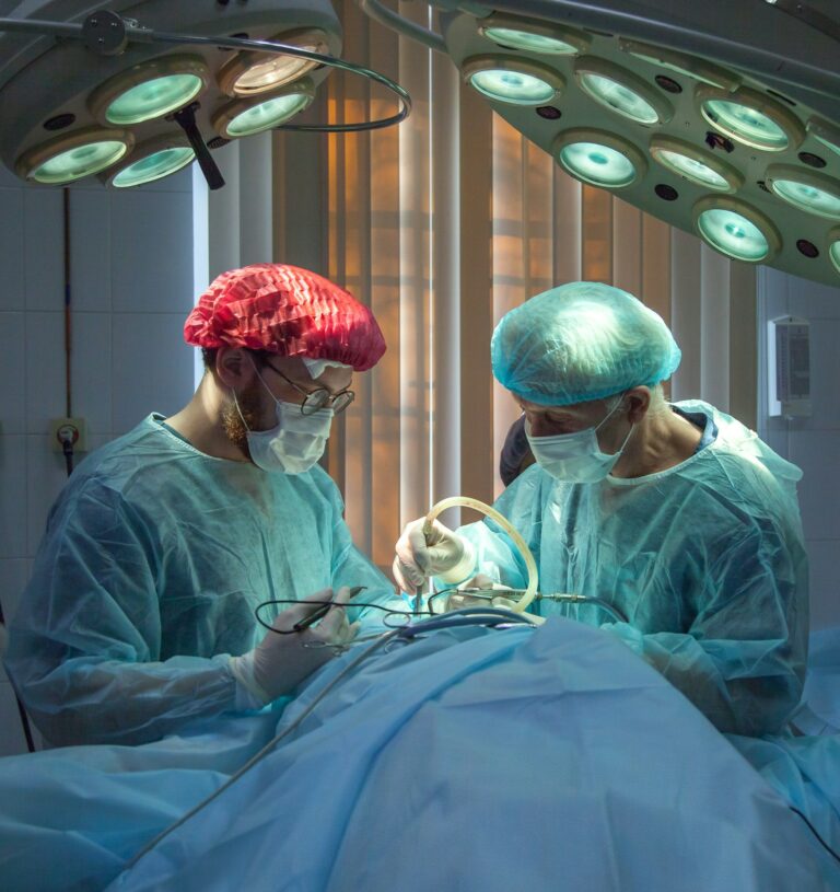Deux professionnels de santé masqués sous les lampes d’un bloc opératoire