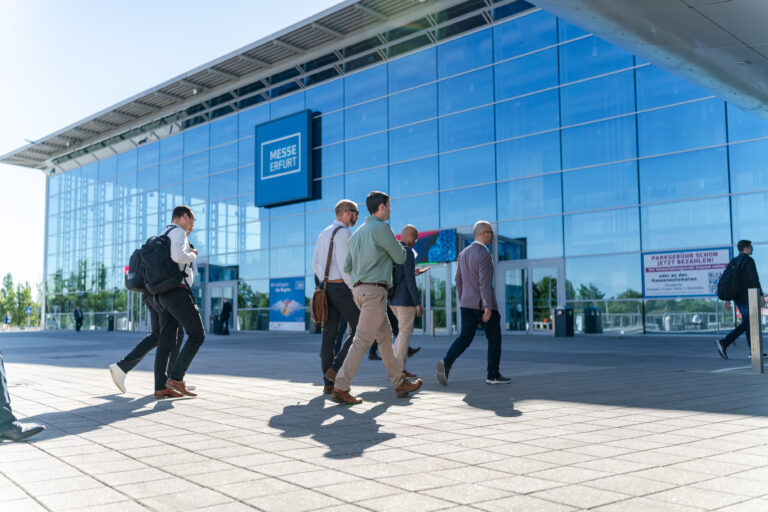 Visitors outside the glass-fronted Messe Erfurt building.
