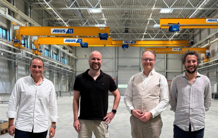 Image of 4 men in front a manufacturing machine