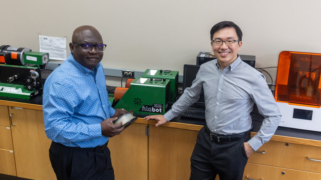 Two men in front of a 3D printer