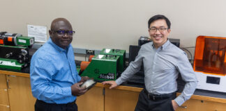 Two men in front of a 3D printer