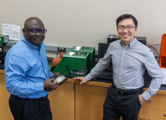 Two men in front of a 3D printer