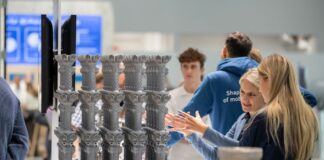 Nikon SLM Solutions enhances AM productivity across multiple areas of the manufacturing chain Two women discussing in front of a build platform of 3D printed parts