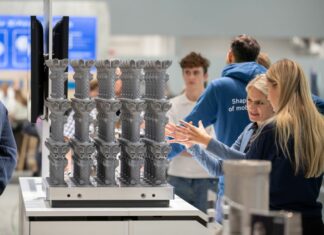 Nikon SLM Solutions enhances AM productivity across multiple areas of the manufacturing chain Two women discussing in front of a build platform of 3D printed parts
