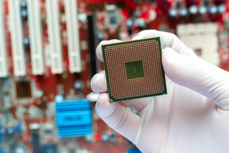 Gloved hand holding a semiconductor chip.