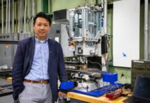 Hang Yu, associate professor of materials science and engineering, with a miniaturized additive friction stir deposition machine used in his advanced manufacturing research. Photo by Peter Means for Virginia Tech.