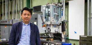 Hang Yu, associate professor of materials science and engineering, with a miniaturized additive friction stir deposition machine used in his advanced manufacturing research. Photo by Peter Means for Virginia Tech.