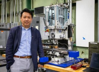 Hang Yu, associate professor of materials science and engineering, with a miniaturized additive friction stir deposition machine used in his advanced manufacturing research. Photo by Peter Means for Virginia Tech.