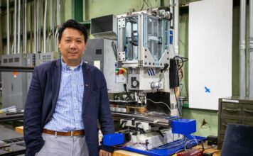 Hang Yu, associate professor of materials science and engineering, with a miniaturized additive friction stir deposition machine used in his advanced manufacturing research. Photo by Peter Means for Virginia Tech.