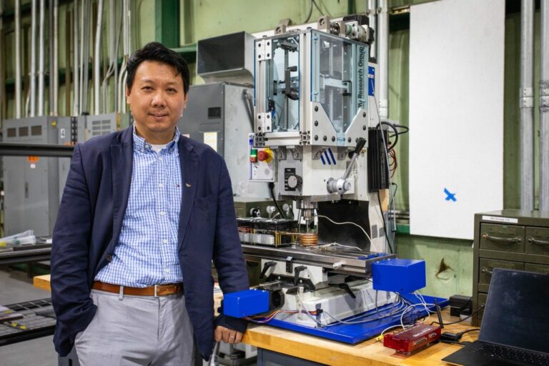 Hang Yu, associate professor of materials science and engineering, with a miniaturized additive friction stir deposition machine used in his advanced manufacturing research. Photo by Peter Means for Virginia Tech.