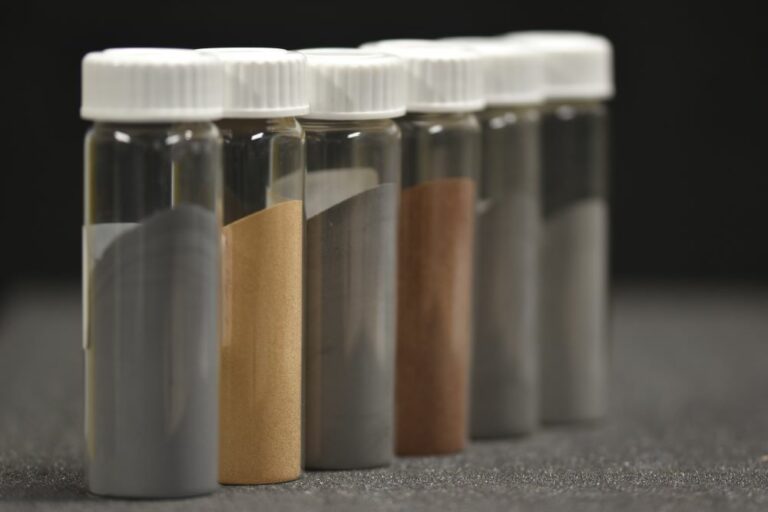 Rangées de flacons en verre fermés contenant des poudres de différentes couleurs.