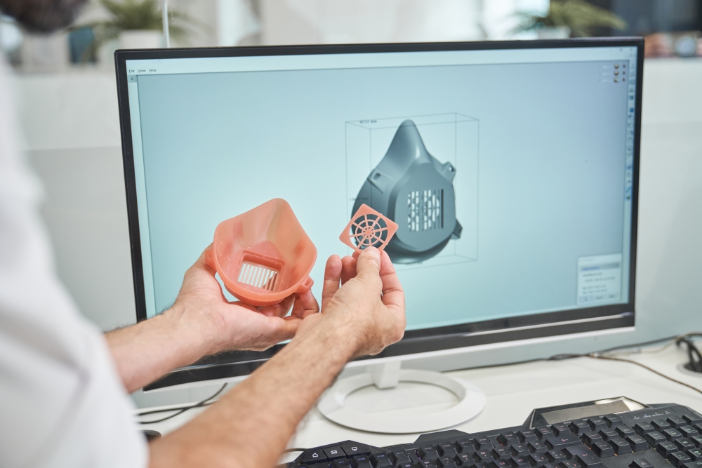 Pièce imprimée en 3D devant un écran affichant sa conception