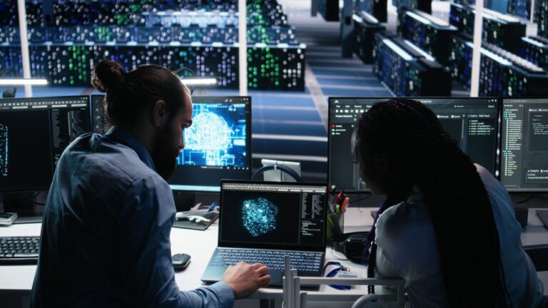 Two people reviewing production data on screens in a factory
