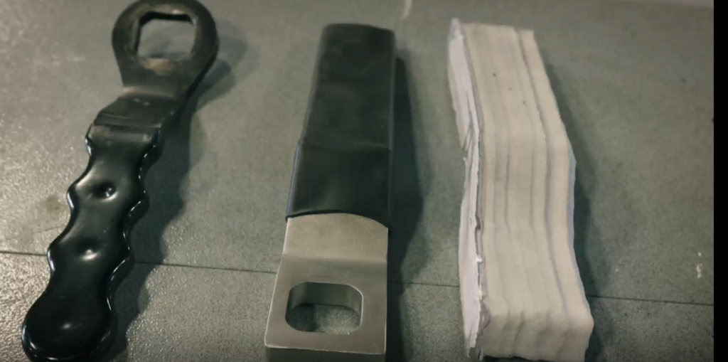 Left to right: Original MRAP Battle Lock Handle component next to Cold Spray additively manufactured finished replacement and initial print variations using the (SPEE3D) Expeditionary Manufacturing Unit (EMU). Source: SPEE3D YouTube Video