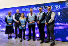 Group of people (2 women and 3 men) taking a picture at the entrance of a center