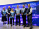 Group of people (2 women and 3 men) taking a picture at the entrance of a center