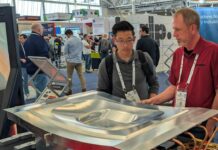 One expert showing a booth visitor a Cut Layer part on display at RAPID+TCT 2026