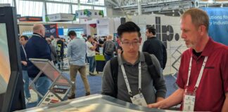One expert showing a booth visitor a Cut Layer part on display at RAPID+TCT 2026