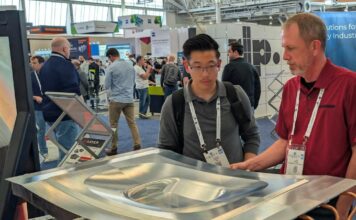 One expert showing a booth visitor a Cut Layer part on display at RAPID+TCT 2026