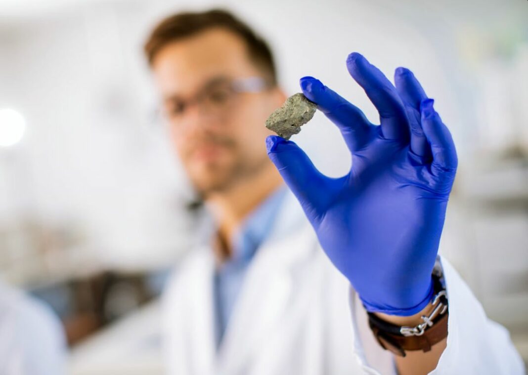 Sicentist showing a part in metal