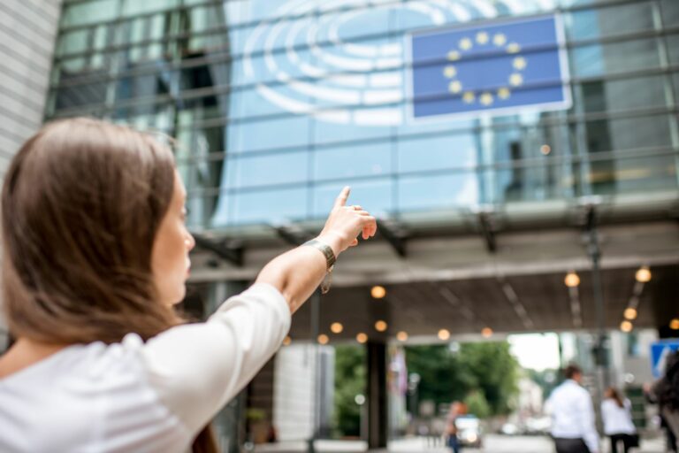 A person points towards a modern glass-fronted building.