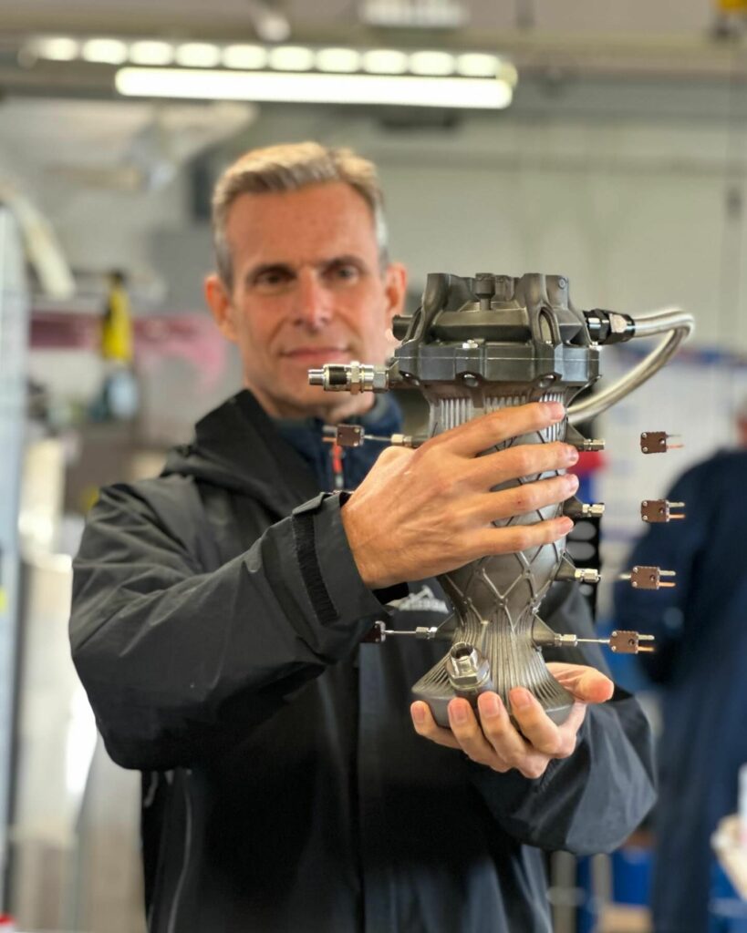 Lin Kayser holding a fully instrumented 6 kN KeroLOX thruster. Printed in Inconel 718 using an HBD metal additive manufacturing system.