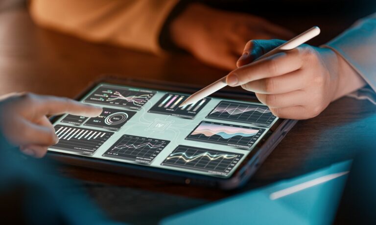 Mains utilisant une tablette affichant des tableaux de bord industriels.