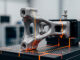 A 3D printed metal part being inspected on a quality control machine in a factory