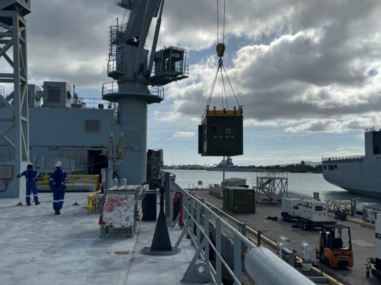 Crane lifting a shipping container onto a vessel.