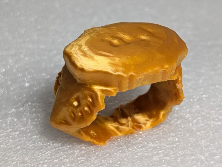 The gold Ilminster Ring displayed on a light grey surface.