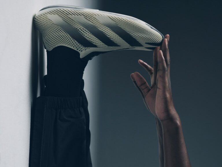 Hand holding the sculpted, openwork adidas Futurecool sneaker.
