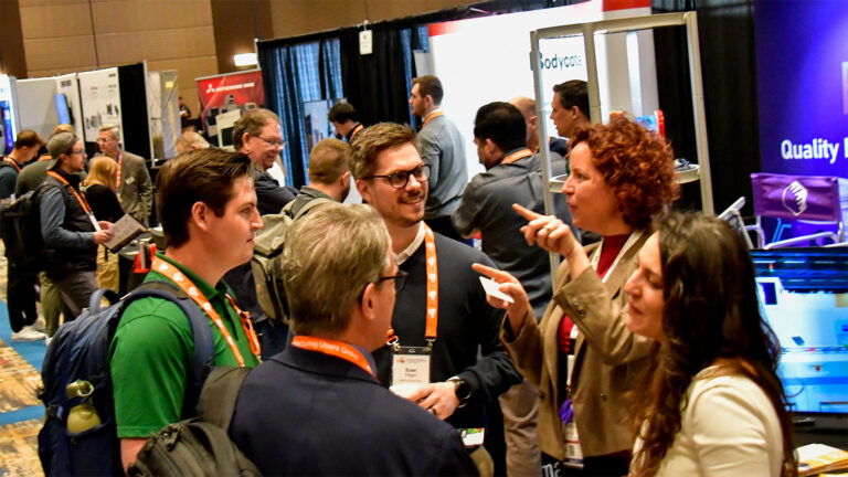 Visitors and exhibitors in a busy conference exhibition hall.