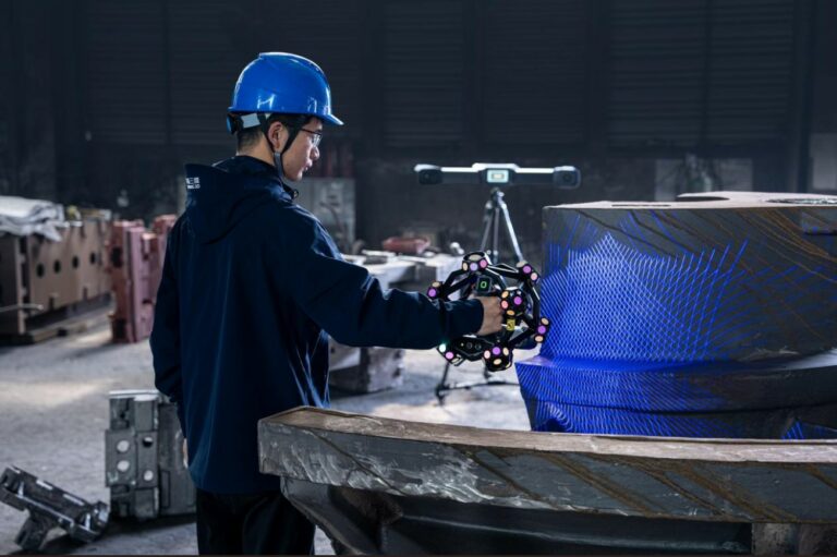 Operator using a handheld 3D scanner on a large cylindrical component.