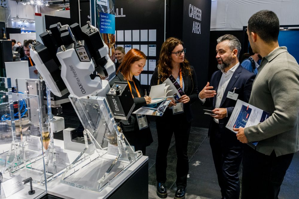 Visitors discussing additive manufacturing at an exhibition stand.