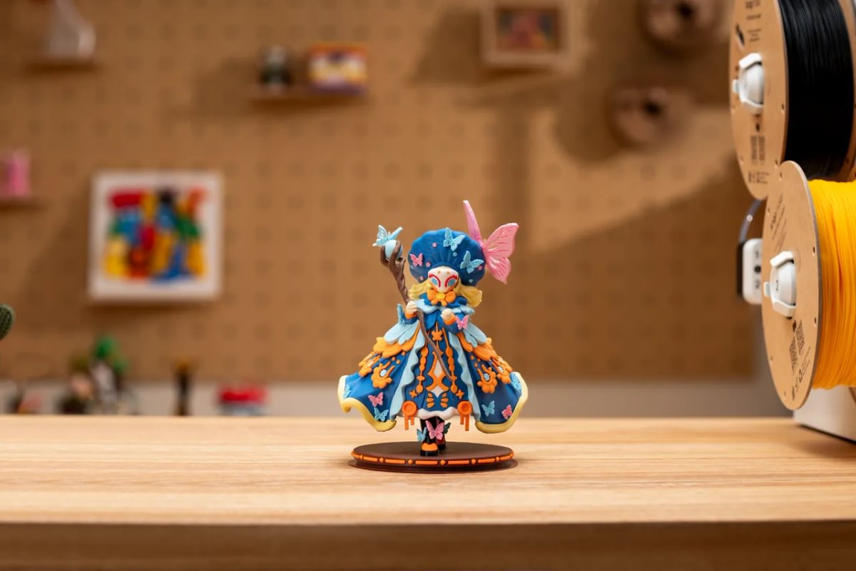 Multicolour 3D printed figurine displayed beside filament spools.
